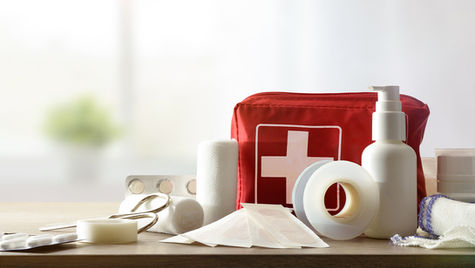 A first aid kit with some of the supplies scattered around it.