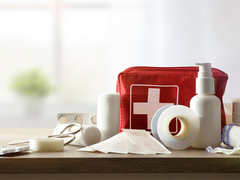 A first aid kit with some of the supplies scattered around it.