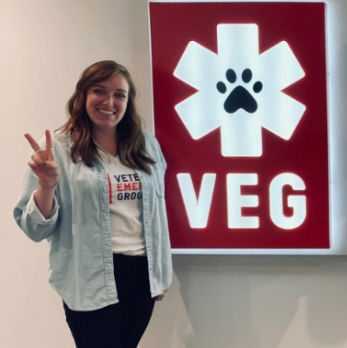 Veterinary nurse with brown hair and blue shirt throwing a peace sign