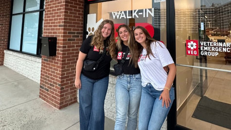 Three women stading in front of a VEG ER for Pets hospital, wearing VEG t-shirts and smiling.