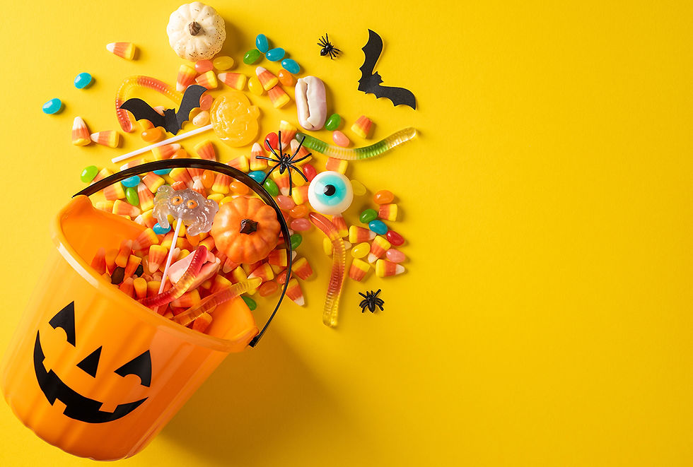 Halloween candy is spilled out of a bucket with a pumpkin face on it.