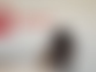 A black dog is sitting and being pet by a veterinary staff member wearing scrubs.