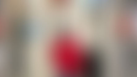 A VEG employee in a red jacket and black had gives a V sign with their fingers to the camera. 
