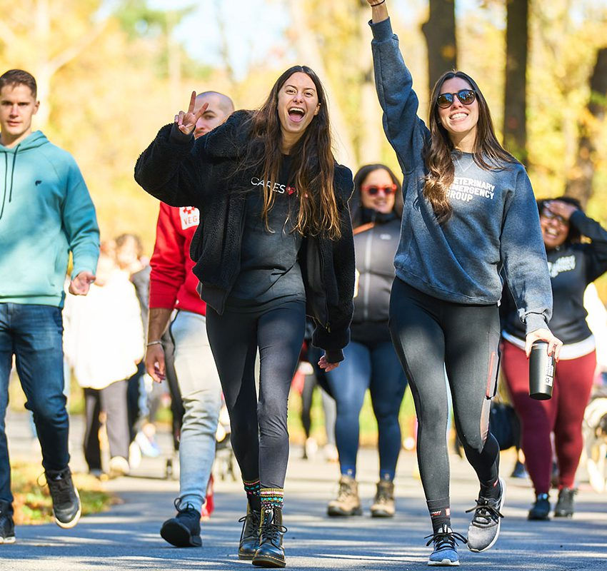 A smiling veterinary staff walks together outdoors during the fall season.